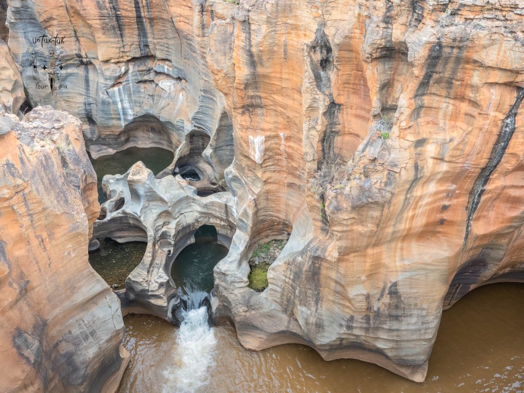 Vue aérienne des gorges formées par l'eau dans des roches aux teintes brunes et ocre.