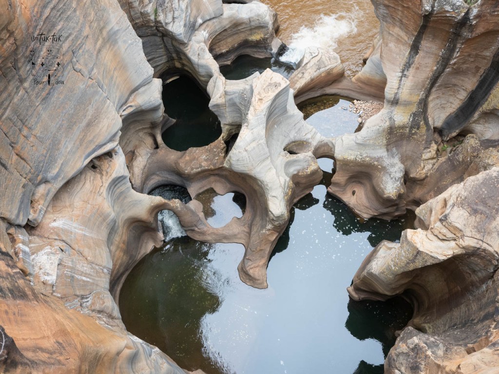 Vue aérienne d'un paysage rocheux avec des bassins d'eau claire et des formations de pierre sculptées par l'érosion.