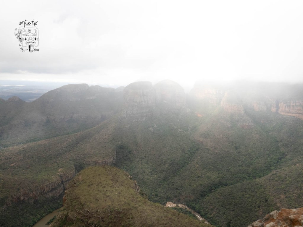 Vue panoramique des montagnes embrumées avec un paysage verdoyant en contrebas.